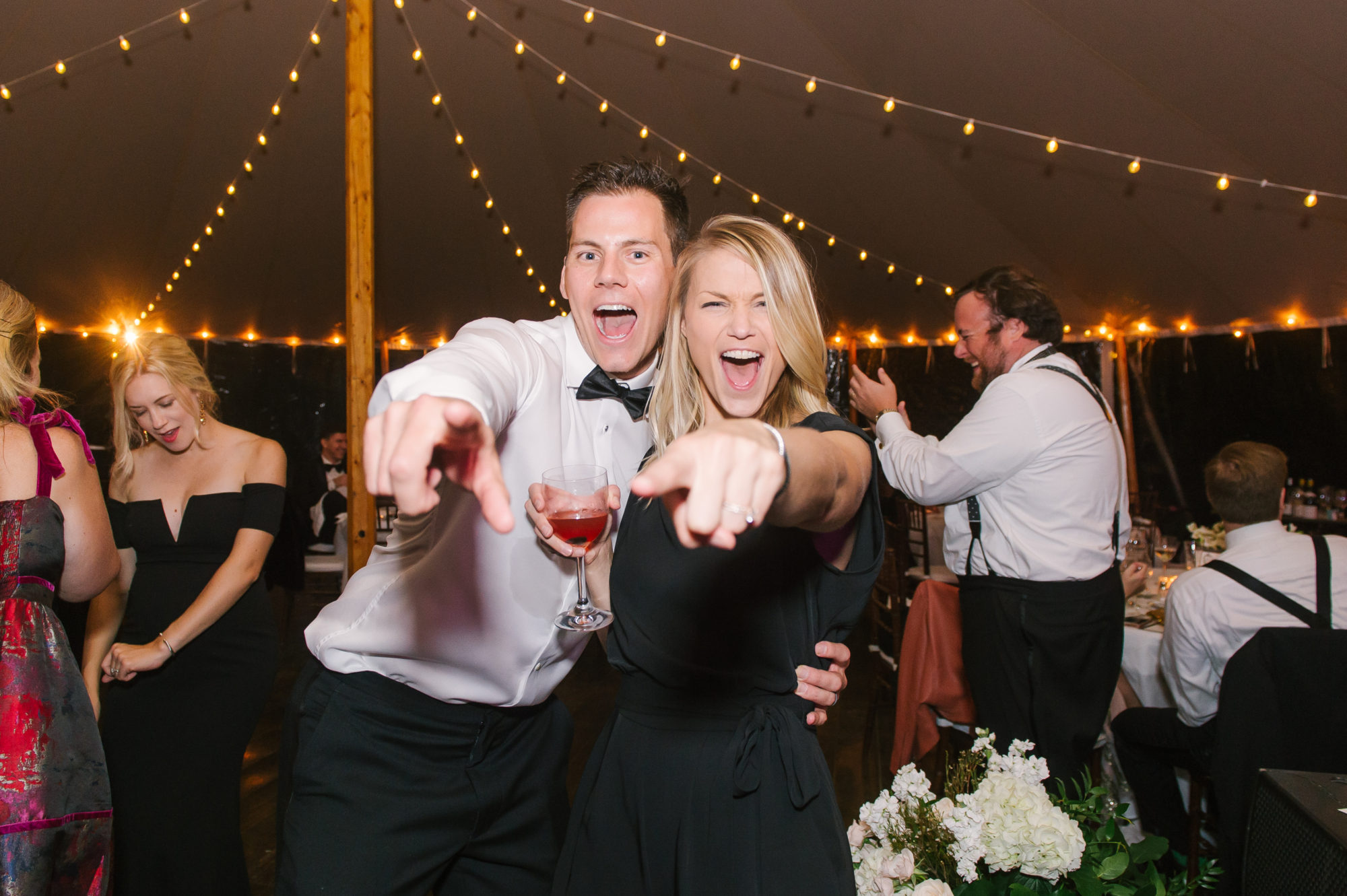 Wedding Photography Tips: How to Take Gorgeous Indoor Wedding Photos by popular New England photographer, Shannon Shipman: image of a man and a woman smiling and pointing at the camera. 