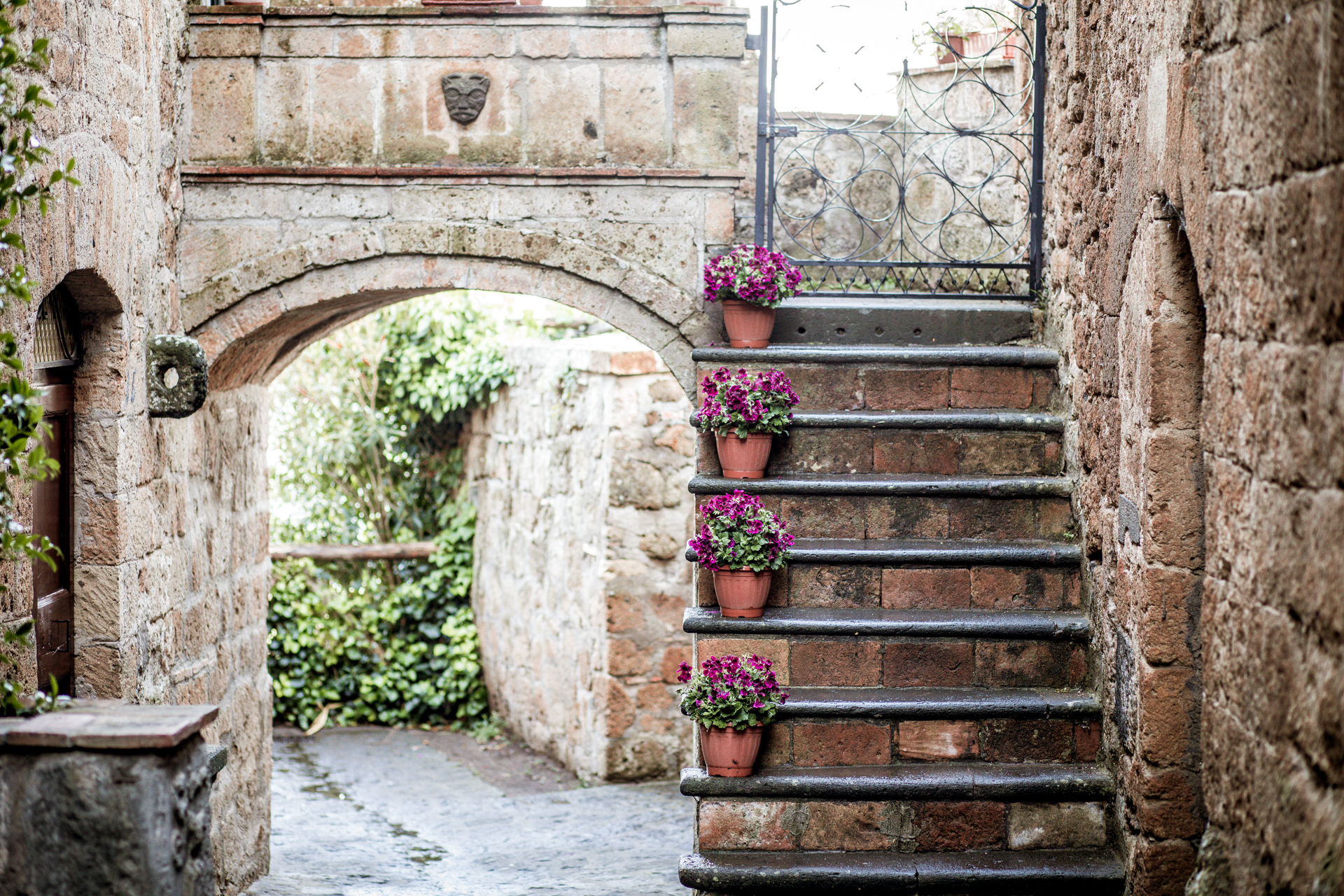10 Gorgeous Views in Tuscany Italy | Tuscany Photos by popular New England travel blogger, Shannon Shipman: image of a stone staircase in Tuscany, Italy with terra cotta pots resting on each step and containing purple flowers. 